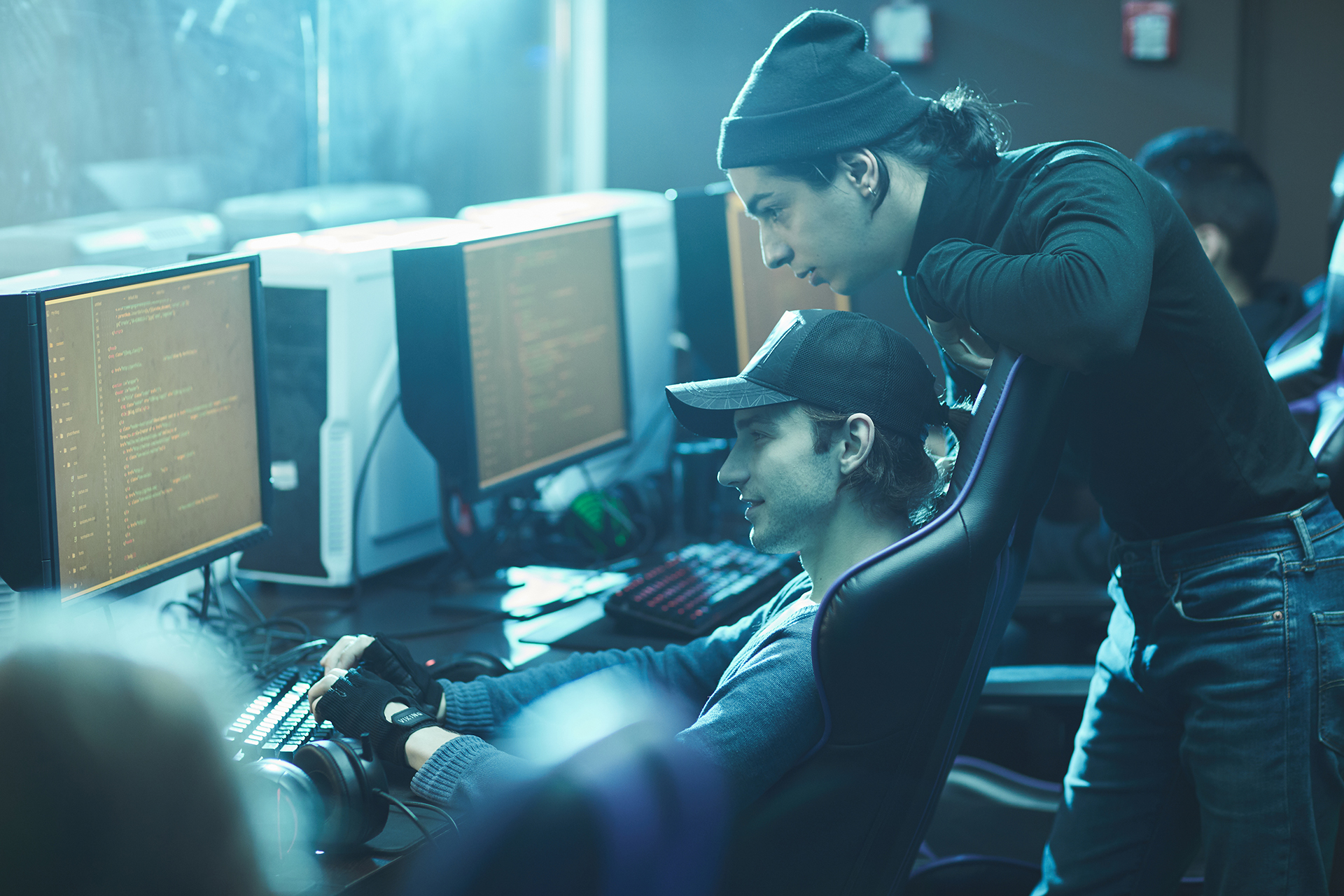 Pensive young computer programmers in headwear working together and analyzing code of new app